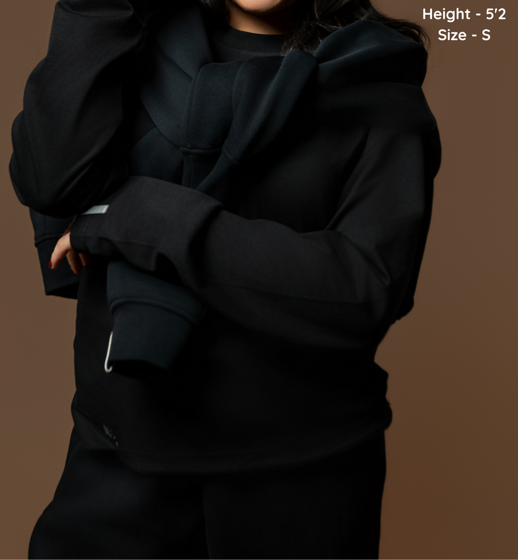 Person wearing a black hoodie on a brown background